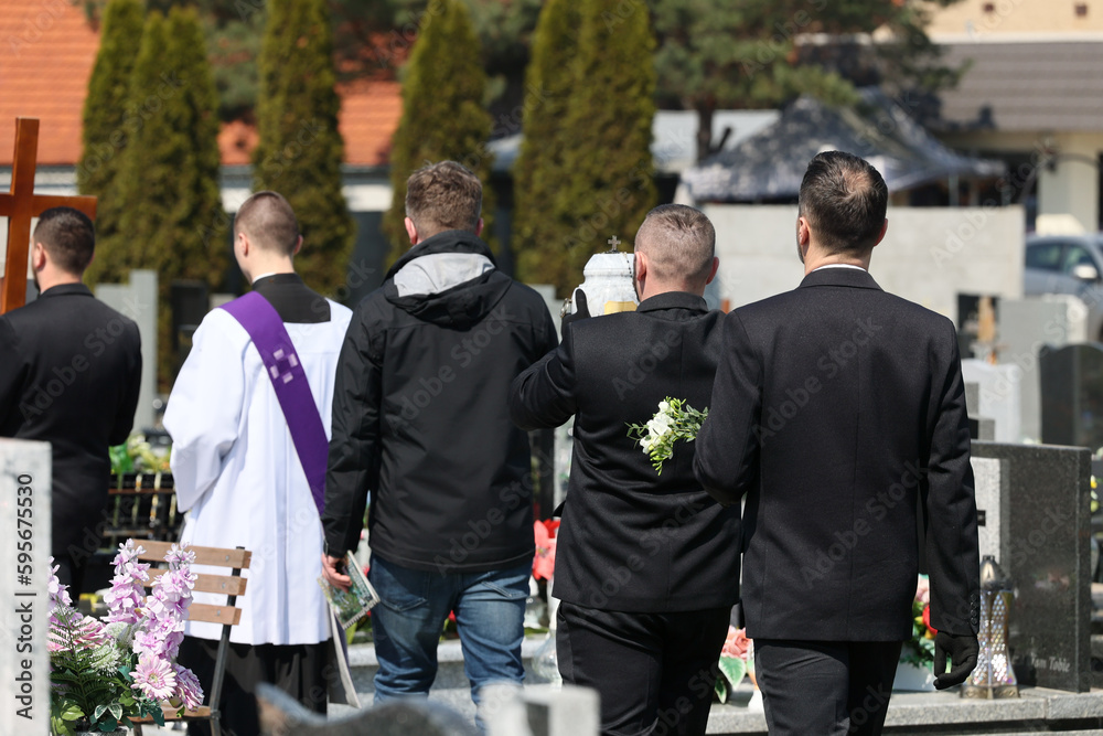 Ksiądz katolicki w komży z fioletowa stułą podczas celebracji pogrzebu.  - obrazy, fototapety, plakaty 