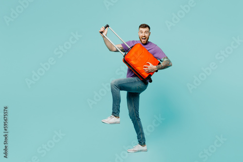 Young traveler man wear casual clothes hold suitcase pov guitar isolated on plain pastel green color background. Tourist travel abroad in free spare time rest getaway. Air flight trip journey concept.