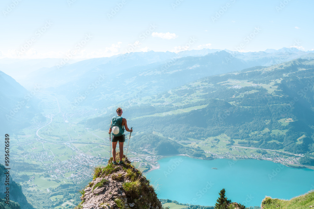 An athletic woman enjoys the scenic view from a beautiful vantage point on Walensee lake in the morning. Schnürliweg, Walensee, St. Gallen, Switzerland, Europe.