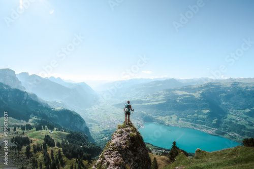 A sporty woman enjoys the view from a beautiful vantage point on Walensee lake in the morning. Schnürliweg, Walensee, St. Gallen, Switzerland, Europe.