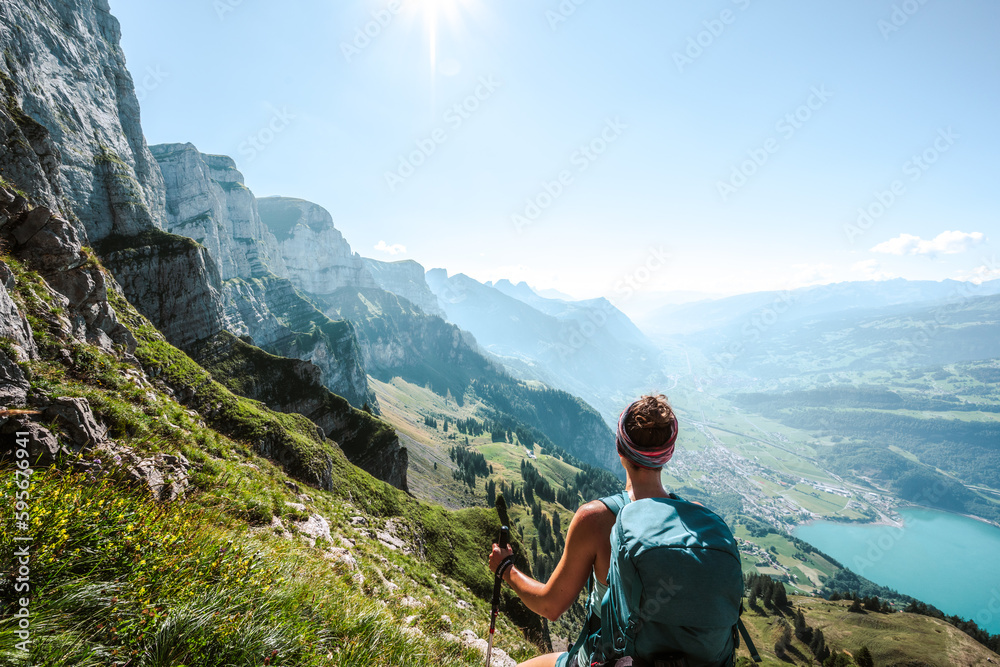 Sporty woman enjoys epic view on the Churfürsten mountain range from hike trail below steep rock wall. Schnürliweg, Walensee, St. Gallen, Switzerland, Europe. - obrazy, fototapety, plakaty 