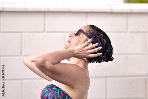 Photograph of a young woman just out of the swimming pool and drying herself in the sun, placed in profile to the camera. With painted nails. Portrait photo in profile. selective focus. Space to copy