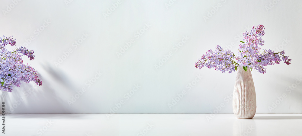Lilac branches in a vase on a white table with copy space Lilac branches in a vase on a white table with copy space