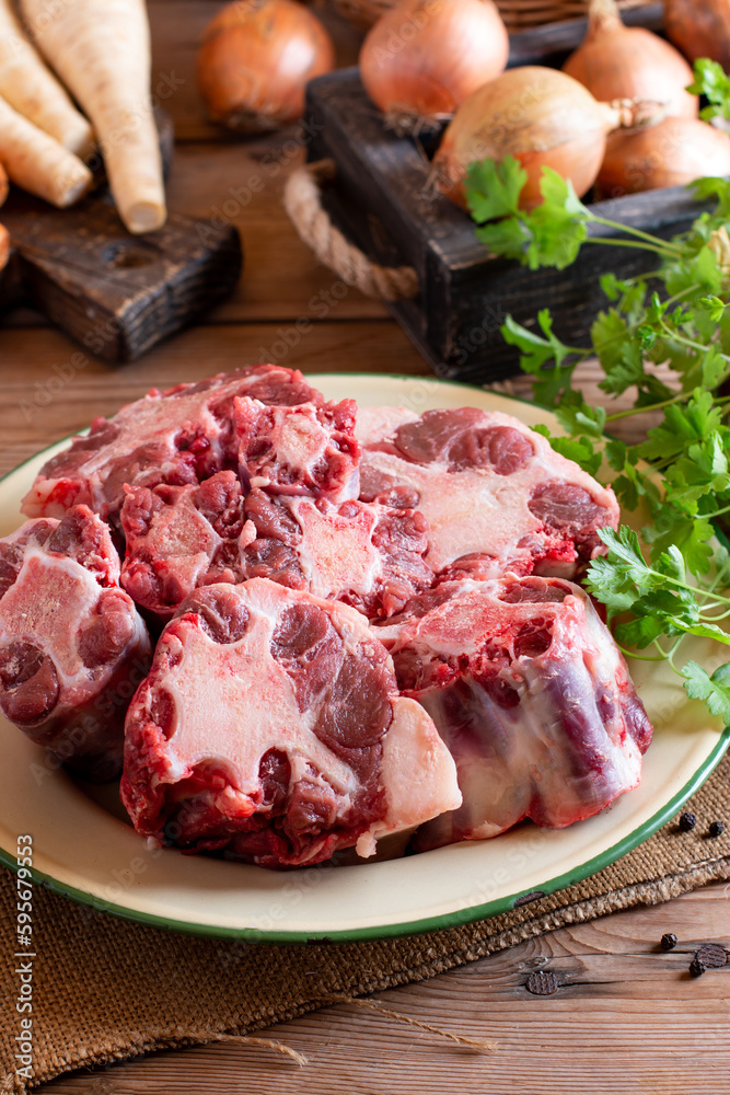 Raw oxtail, the culinary name for the tail of cattle, ready to be cooked. On a wooden board Raw oxtail, the culinary name for the tail of cattle, ready to be cooked. On a wooden board
