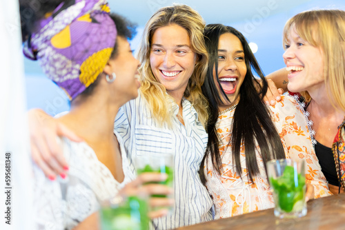 Smiling women having fun outdoor at beach party while drinking mojito