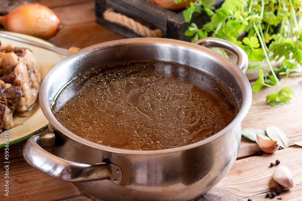 Saucepan with bouillon with a ladle on wooden table. Bone broth Saucepan with bouillon with a ladle on wooden table. Bone broth