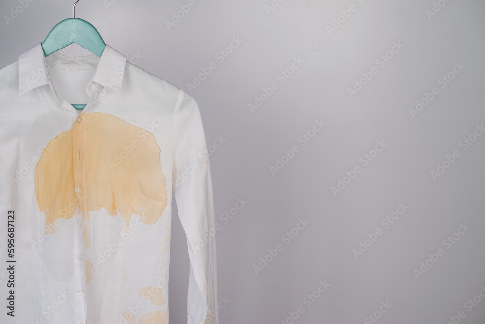 Fototapeta premium Women's office white shirt with a stain of coffee on a white background. Copy space. 