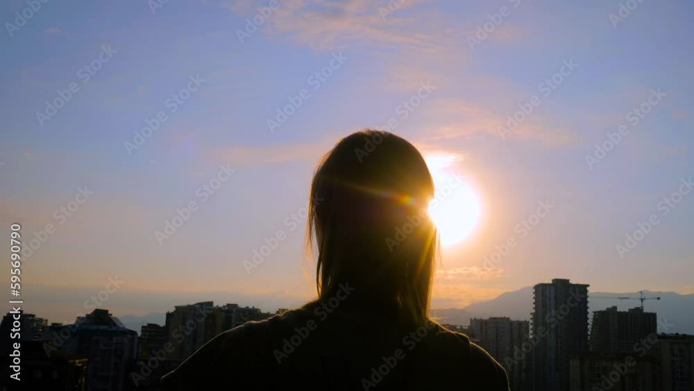 Back view: portrait of active woman silhouette is stretching arms up against the sunrise sky with sun lens flare. Freedom, waking up, sport, awake, morning and happiness concept Back view: portrait of active woman silhouette is stretching arms up against the sunrise sky with sun lens flare. Freedom, waking up, sport, awake, morning and happiness concept