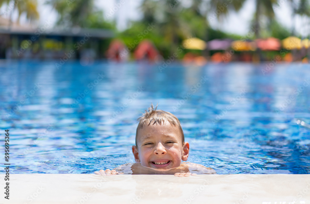 Little blond boy is having fun in the outdoor pool in Maldives