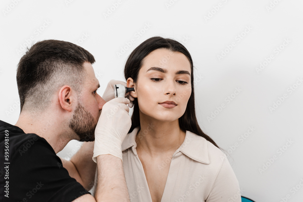 ENT doctor with otoscope. Otoscopy. Otolaryngologist looks through otoscope the ears of woman. Treatment ear pain. ENT doctor with otoscope. Otoscopy. Otolaryngologist looks through otoscope the ears of woman. Treatment ear pain.