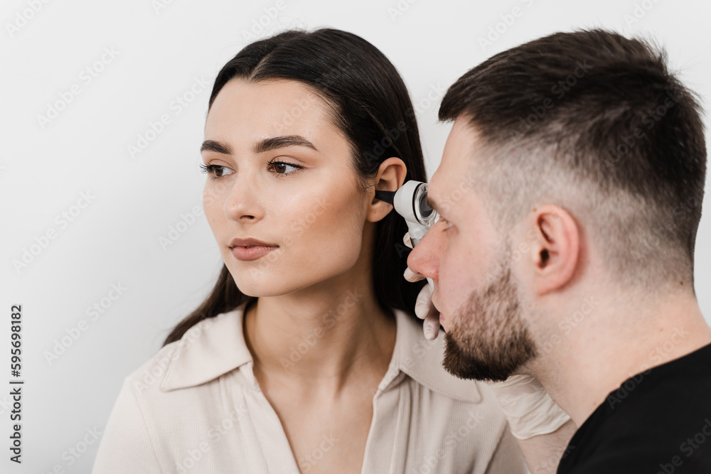 Close-up examination of womans ear with otoscope. Otoscopy. Visit to ENT doctor and consultation. Close-up examination of womans ear with otoscope. Otoscopy. Visit to ENT doctor and consultation.