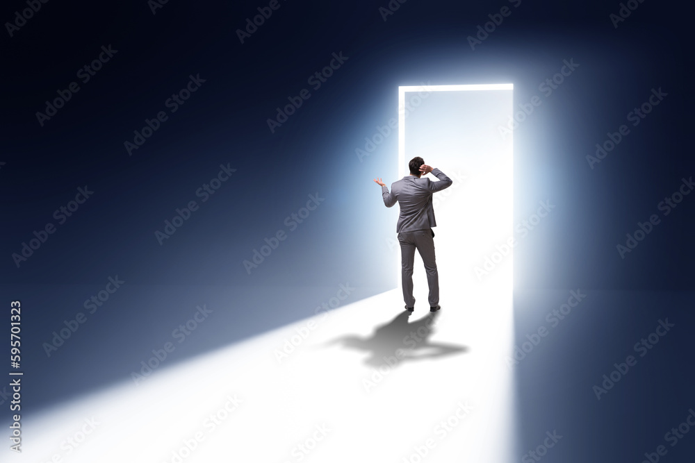 Businessman entering backlit door in escape concept Businessman entering backlit door in escape concept