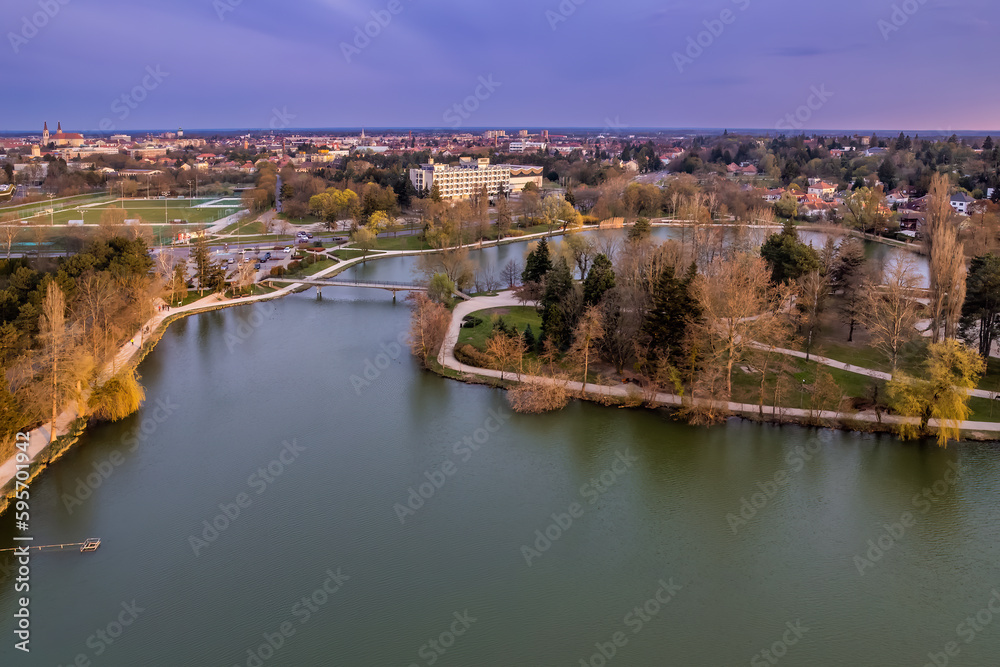 Fototapeta premium Birds eye shot of the Boating Lake of Szombathely, Hungary with the city's view in the background 