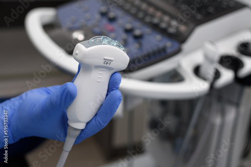 Close-up of ultrasound diagnostic probe. A doctor's hands hold a transducer with gel for diagnosing internal organs using modern ultrasound technology, including elastography and sonography. photo