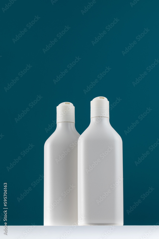 A white mock-up of a bottles with cosmetic accessories on a white shelf. Shower gel with a place for your logo. A white mock-up of a bottles with cosmetic accessories on a white shelf. Shower gel with a place for your logo.
