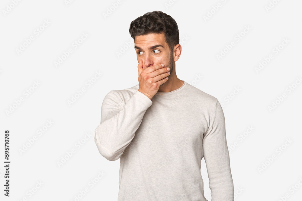 Young handsome man isolated thoughtful looking to a copy space covering mouth with hand. Young handsome man isolated thoughtful looking to a copy space covering mouth with hand.