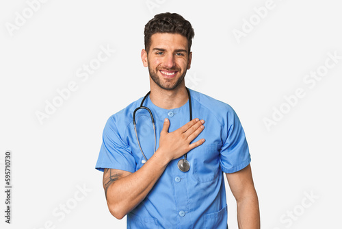 Young nurse man laughs out loudly keeping hand on chest.