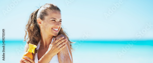 Принти на полотні Young woman on beach applying sun block creme and looking on cop