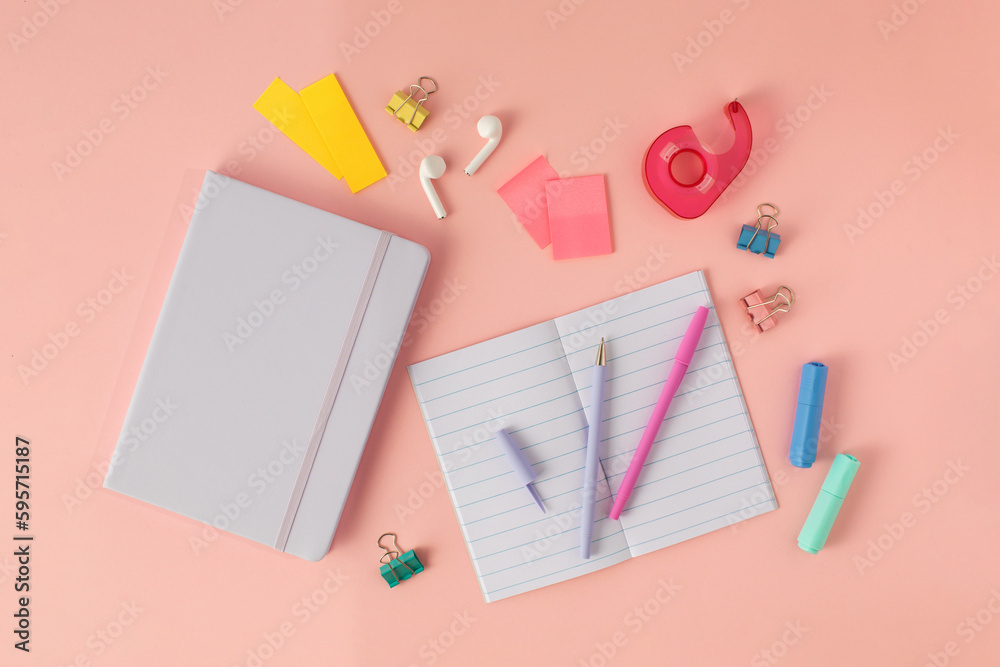 Notepad, pens and wireless headphones on a pink background. Online learning, desktop. Notepad, pens and wireless headphones on a pink background. Online learning, desktop.