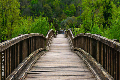 Wooden bridge with arches surrounded by vegetation in the town of Castellfollit de la Roca