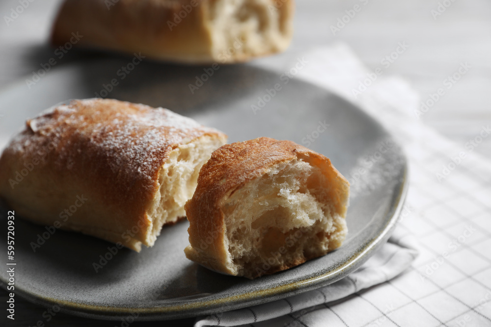 Fresh crispy ciabattas on white checkered tablecloth, closeup