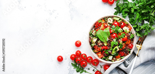 Quinoa tabbouleh salad with red cherry tomatoes, orange paprika, avocado, cucumbers and parsley. Traditional Middle Eastern and Arabic dish. White table background, top view banner