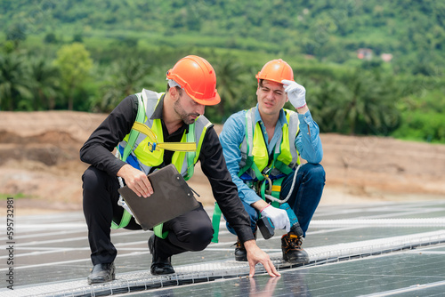 Wallpaper Mural Two young engineer and inspector wearing safety vest and hard helmet inspecting solar panel by kneeling and filling holes and fixing damage using a drill machine while holding a clipboard Torontodigital.ca