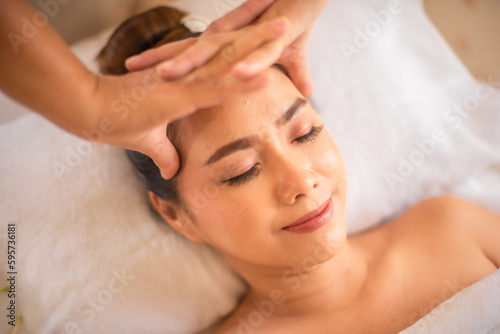 Professional masseuse massaging the head of a happy beautiful asian client.