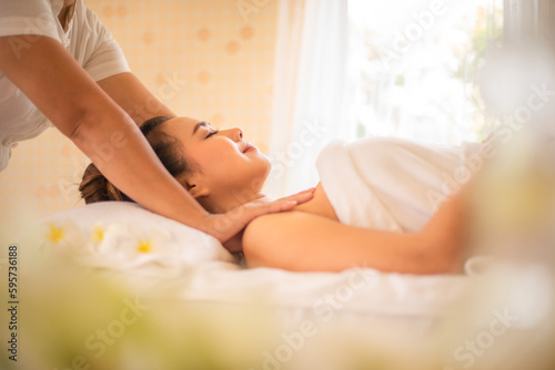 Side view of masseuse used her skilled hands to knead and apply pressure to the muscles of the beautiful asian customer's shoulders.
