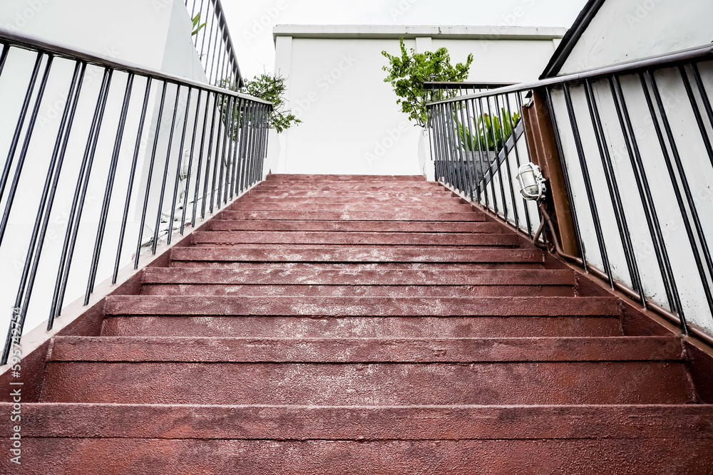 Red cement steps in the city Closeup concrete staircase with railing, old staircase detail, abstract stone staircase background. Red cement steps in the city Closeup concrete staircase with railing, old staircase detail, abstract stone staircase background.