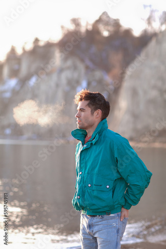 Young handsome man in the winter park by the lake
