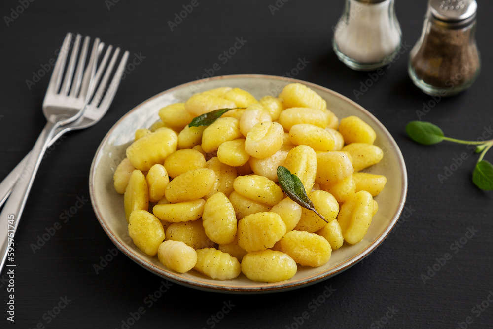 Homemade Easy Potato Gnocchi on a Plate on a black background, side view. Homemade Easy Potato Gnocchi on a Plate on a black background, side view.