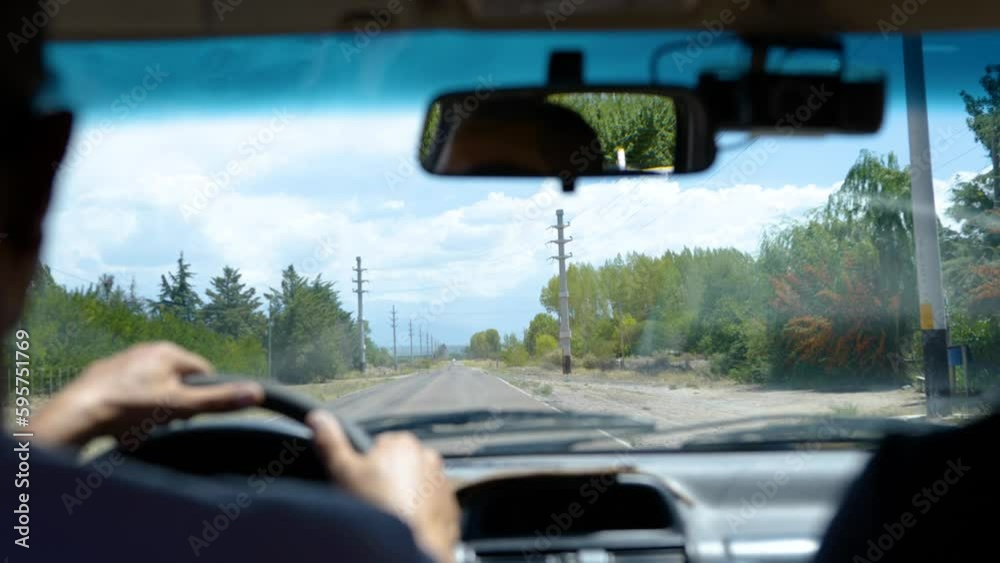 A man drives down the road in Mendoza, Argentina in slow motion and puts his hand to the wheel A man drives down the road in Mendoza, Argentina in slow motion and puts his hand to the wheel