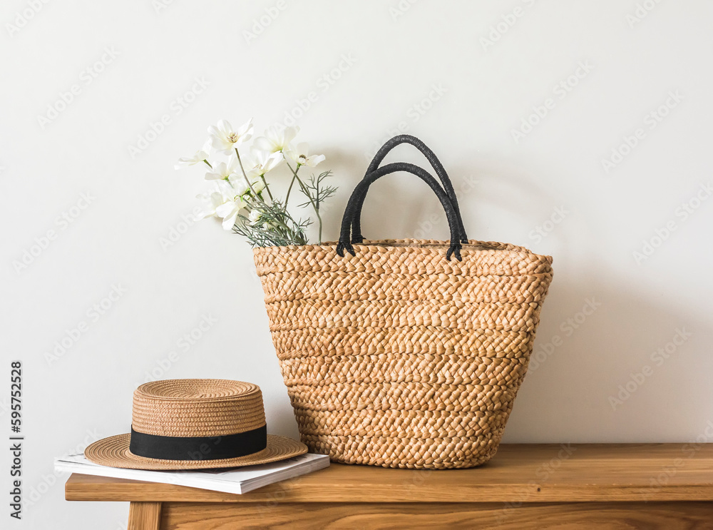 A wicker straw summer bag, a hat and a magazine on a wooden bench. Summer season - obrazy, fototapety, plakaty 