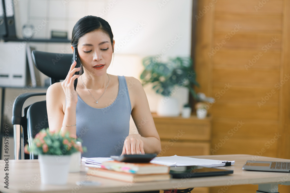 A portrait of a beautiful, professional, and confident millennial Asian businesswoman making business calls at home office. A portrait of a beautiful, professional, and confident millennial Asian businesswoman making business calls at home office.