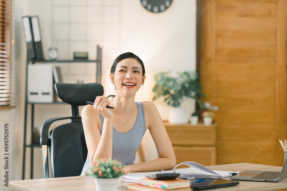 Portrait of a happy millennial Asian businesswoman working remotely from her home office. Warm tone Portrait of a happy millennial Asian businesswoman working remotely from her home office. Warm tone