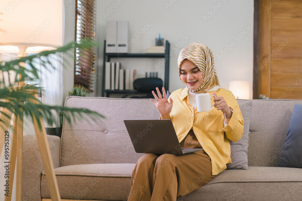 Foto de Muslim woman is shown having a video call on her laptop in a ...