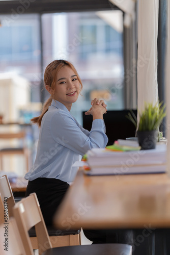 happy young businesswoman Asian siting on the chairs cheerful demeanor raise holding coffee cup smiling looking laptop screen .Making opportunities female working successful in the office.