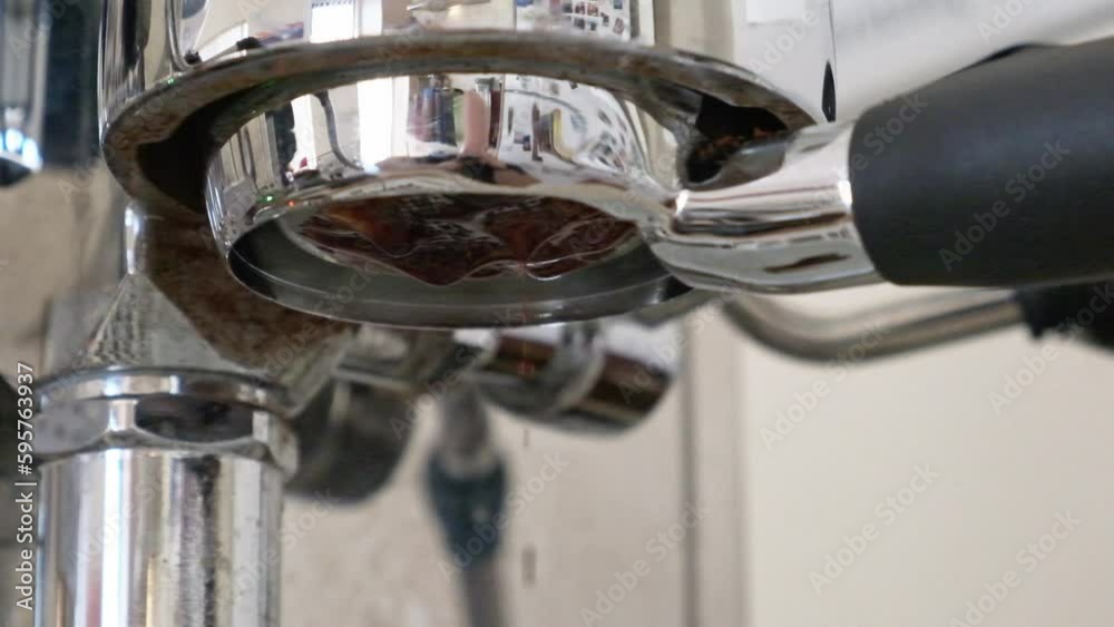 Espresso extracting and slowly dripping closeup from a bottomless filter in slow motion Espresso extracting and slowly dripping closeup from a bottomless filter in slow motion
