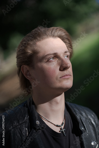 A young gender-fluid model (he / she / they) stands for an outdoor portrait, with dramatic lighting. They look up into the distance, expressing contemplation. © Levi Meir Clancy
