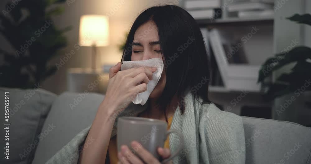 Footage of Sick young Asian woman caught cold and cough while drinking hot water on big comfy