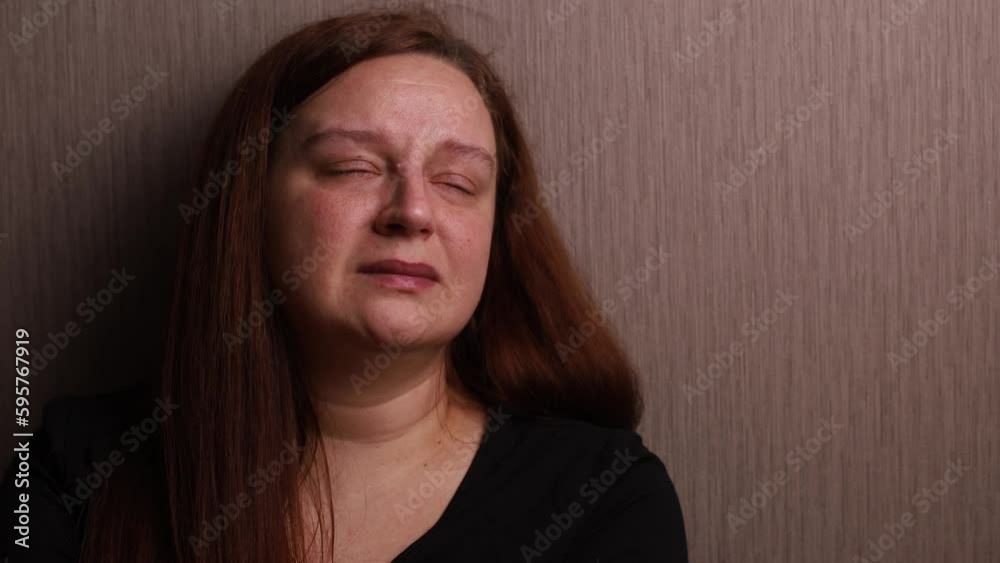 Sad woman bitterly cry near room wall. Tears roll down cheeks, tearful eyes and swollen face. Splash out emotions, sob violently. Emotional breakdown, mental health problems. Depression and hysterics.