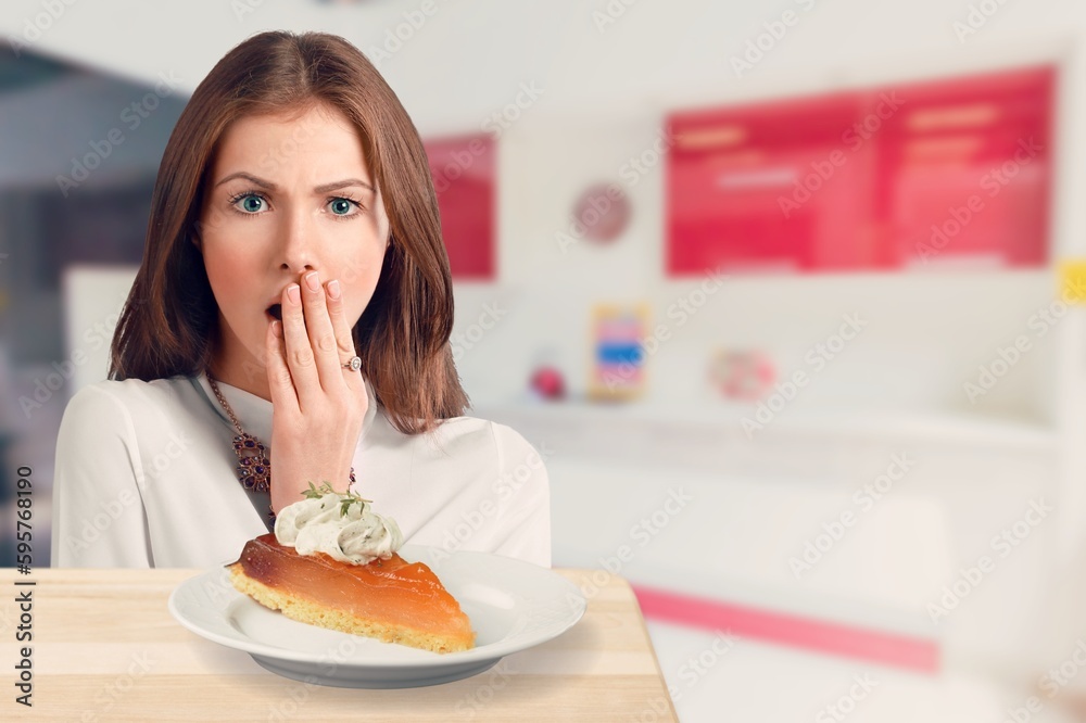 Funny young woman eating tasty sweet cake