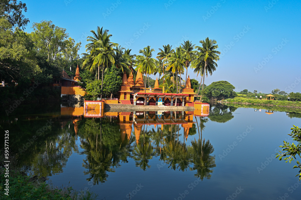 Temple on the lake. Hindu Temple. Palm trees and lake. Blue Sky. Lovely Water reflection. Maharashta. india