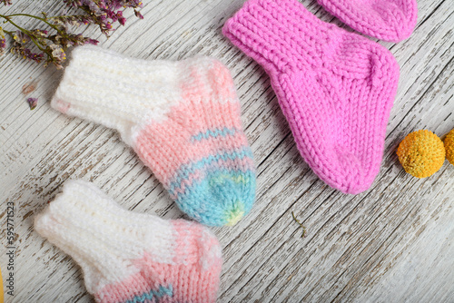 Small baby socks, made of cotton yarn, on white wooden background