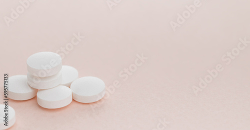 Heap white round pills on pink background with copy space. Health care concept.