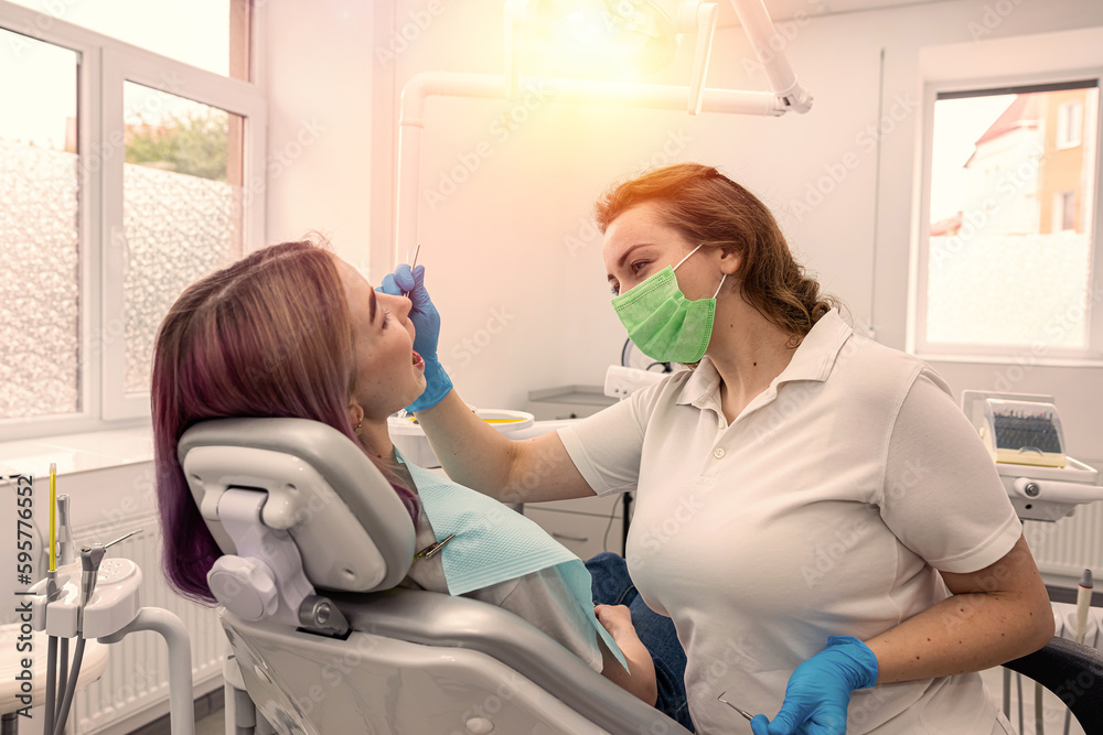 view of a smiling woman's mouth during treatment in a dental clinic by a female dentist. view of a smiling woman's mouth during treatment in a dental clinic by a female dentist.