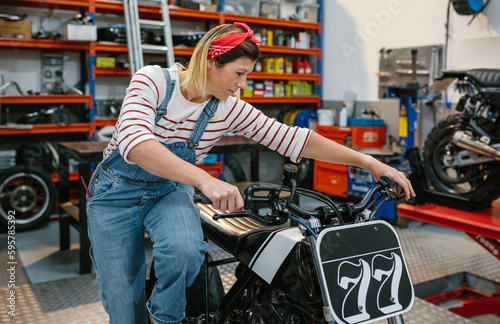 Mechanic woman start engine of custom motorcycle on factory