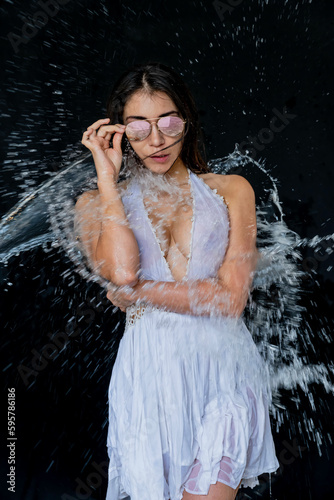 A Lovely Latin Bikini Model Poses In A Studio Environment While Water Is Thrown On Her