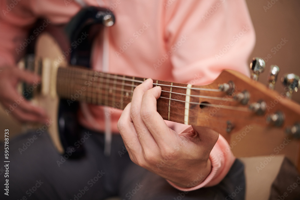 Closeup image of young man enjoying playing electric guitar